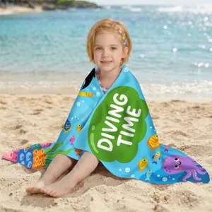 Kind trägt ein Mikrofaser-Strandtuch mit Cartoon-Druck 'Diving Time' an einem sonnigen Strand