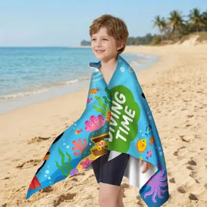 Kind in buntem Mikrofaser-Strandtuch mit Unterwasser-Cartoon-Thema am sonnigen Strand.