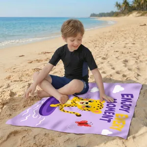 Kind sitzt am sonnigen Strand auf einem lila Mikrofaser-Badetuch mit Cartoon-Leopard