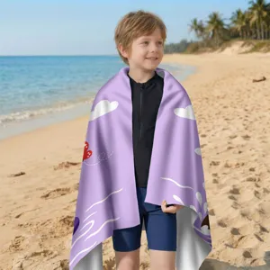 Detailansicht eines Kindes mit einem lila Mikrofaser-Strandtuch an einem sonnigen Strand.