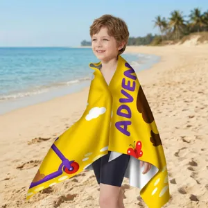 Detailansicht eines gelben Mikrofaser-Strandtuchs mit Abenteuerthema an einem sonnigen Strand.
