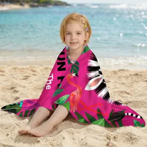 Kind am Strand eingewickelt in ein pinkes Flamingo-Mikrofaser-Badetuch, schnelltrocknend