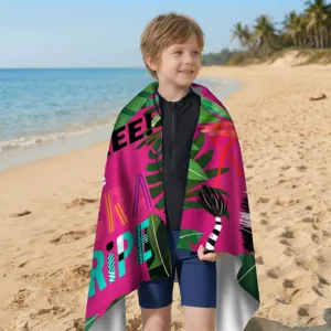Kind in rosa Mikrofaser-Strandtuch mit tropischem Design an einem sonnigen Strand