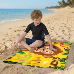 Ein Kind sitzt auf einem farbenfrohen Mikrofaser-Strandtuch mit Affen-Motiv an einem Strand