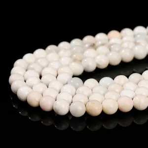 Natural white opal loose round beads shown in a curved arrangement on black surface