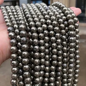 Primer plano de cuentas redondas de pirita natural con brillo metálico para joyería DIY