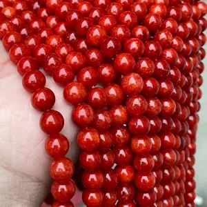 Gros plan de perles rondes en calcédoine rouge vif avec une finition polie pour la bijouterie.
