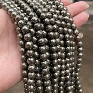 Primer plano de cuentas redondas de pirita natural con brillo metálico para joyas DIY