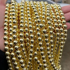 Macro detail of shiny gold electroplated hematite round beads for DIY jewelry making.