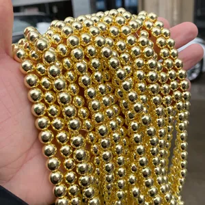 Detailed macro view of shiny gold plated hematite round beads for DIY jewelry making.