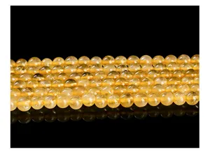 Detailed macro view of natural ice clear golden rutilated quartz round beads on black.