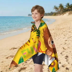 Lächender Junge in einem gelben Mikrofaser-Strandtuch mit Affen-Motiv am Strand.