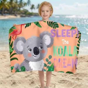 Kind hält ein buntes Mikrofaser-Strandtuch mit Koala- und Flamingo-Print am sonnigen Strand