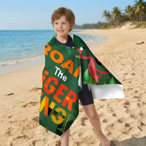 Kind am Strand eingewickelt in ein Mikrofaser-Strandtuch mit tropischem Flamingo-Print