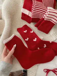 Detailed shot of thick red knit winter socks with cute white hearts and stripes cozy warm.