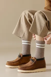 Nahaufnahme von Herren-Winterthermostrickstrümpfen mit Doppelstreifen und Freizeitschuhen.