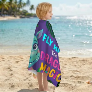 Kind trägt ein lila Mikrofaser-Strandtuch mit Drachenmotiv am sonnigen Strand