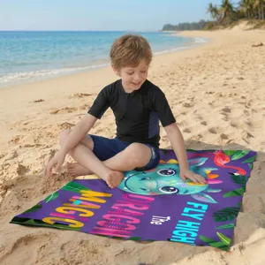 Buntes Mikrofaser-Strandtuch mit Drachenmotiv am sonnigen Sandstrand aus der Nähe