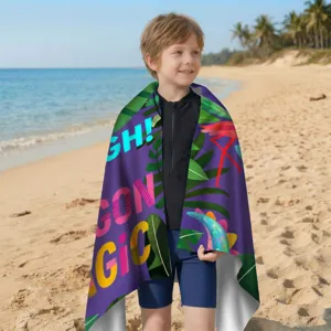 Kleiner Junge am Strand, eingewickelt in ein buntes Mikrofaser-Strandtuch mit Palmen