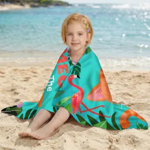 Mädchen eingehüllt in ein Strandtuch aus Mikrofaser mit Flamingo-Print am Ufer