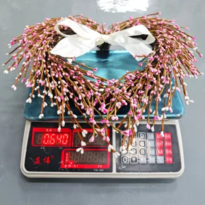 Heart-shaped pink and white berry wreath shown on a digital scale weighing 0.64kg