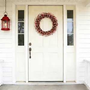 Detailed view of a pink and white berry wreath hanging on a classic white front door