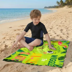 Grünes Mikrofaser-Strandtuch mit Schlangenmuster am Strand mit glücklichem Kind
