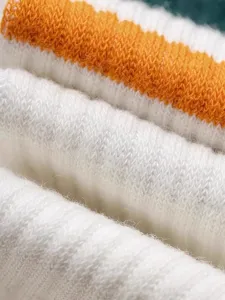 Close-up of soft knitted fabric with white and orange stripes for yoga socks texture detail.