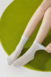 Detail view of sheer white women's mid-calf socks showing delicate breathable fabric and fit.