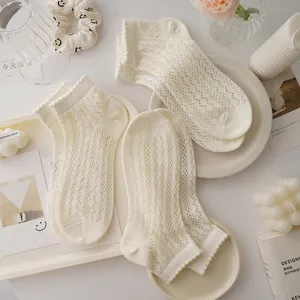 Detailed flatlay view of white hollow-out mesh socks with delicate lace trim, soft cotton.