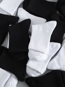 Detailed view of classic black and white ribbed cotton mid-tube socks, breathable fabric.