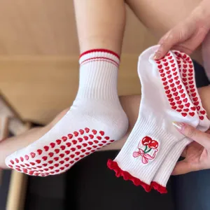 Primo piano di calzini da yoga antiscivolo da donna con ricamo di ciliegie e suola a cuori.
