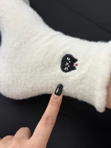 Close-up detail of winter cozy fluffy warm socks featuring a cute black cat embroidery.