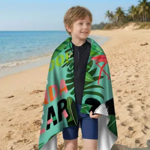 Detailansicht eines Jungen mit einem tropischen Flamingo-Strandtuch am Meer