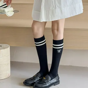 Close-up detail of black knee-high socks featuring white double stripes and a cute bow embroidery.