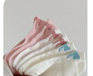 Close-up detail shot of cute short socks with lovely bow embroidery and breathable mesh design.