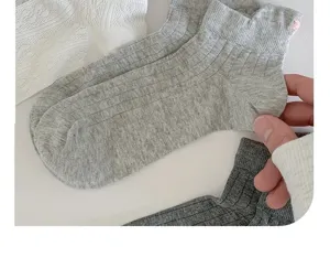 Close-up of grey cotton ankle socks with cute bow detail, soft ribbed knit texture, detail view.