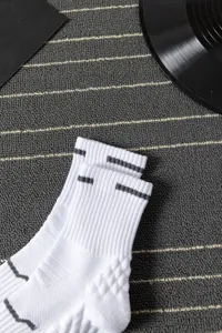 Detailed view of men's white athletic mid-calf socks with towel bottom and grey stripes.