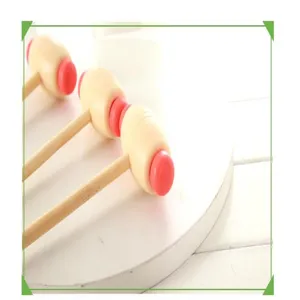 Detailed view of manual wooden massage hammer with red plastic head on white background.