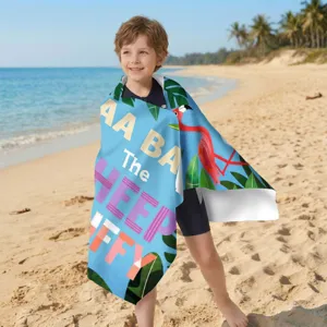 Kind in buntem Flamingo-Druck schnelltrocknendem Mikrofaser-Strandtuch am sonnigen Strand