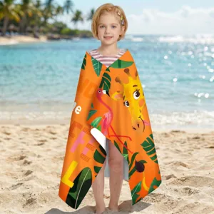 Kind trägt ein Mikrofaser-Strandtuch mit Giraffen- und Flamingo-Muster am sonnigen Strand.