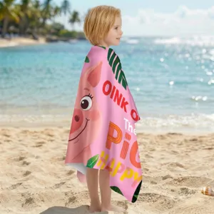 Kind eingehüllt in ein rosa Mikrofaser-Strandtuch mit süßem Schweinchen am Strand