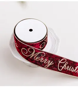 Dettaglio del nastro natalizio in velluto bordeaux con scritta dorata Merry Christmas.