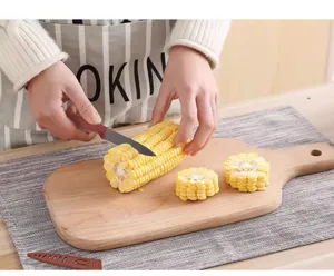 Stainless steel fruit knife detail view showing sharp paring blade cutting fresh corn.
