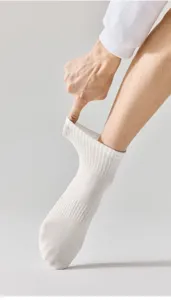 Close-up detail of white athletic cotton socks with ribbed cuff and breathable knit texture.