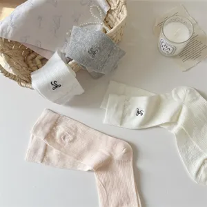 Detailed shot of cute ballet style bow mid-calf socks with delicate embroidery on white.