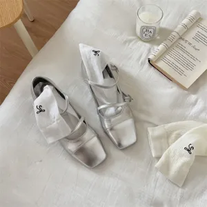 Silver square toe Mary Jane shoes paired with white bow socks, trendy ballet style footwear.