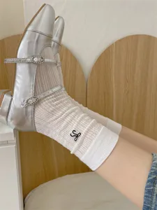 White mesh mid-calf socks featuring black embroidery detail paired with silver Mary Jane shoes.