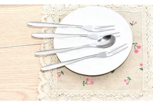 Edelstahl Kuchengabeln und Löffel Set Detailansicht auf weißem Teller und Kirschmatte.