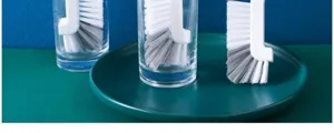 Gros plan de la brosse de nettoyage de tasse à long manche avec poils blancs pour fentes fines.